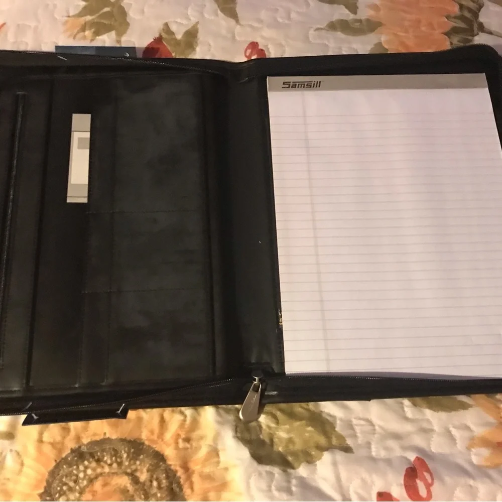 Black portfolio with wraparound zipper. Writing pad, slide and zippered pockets.